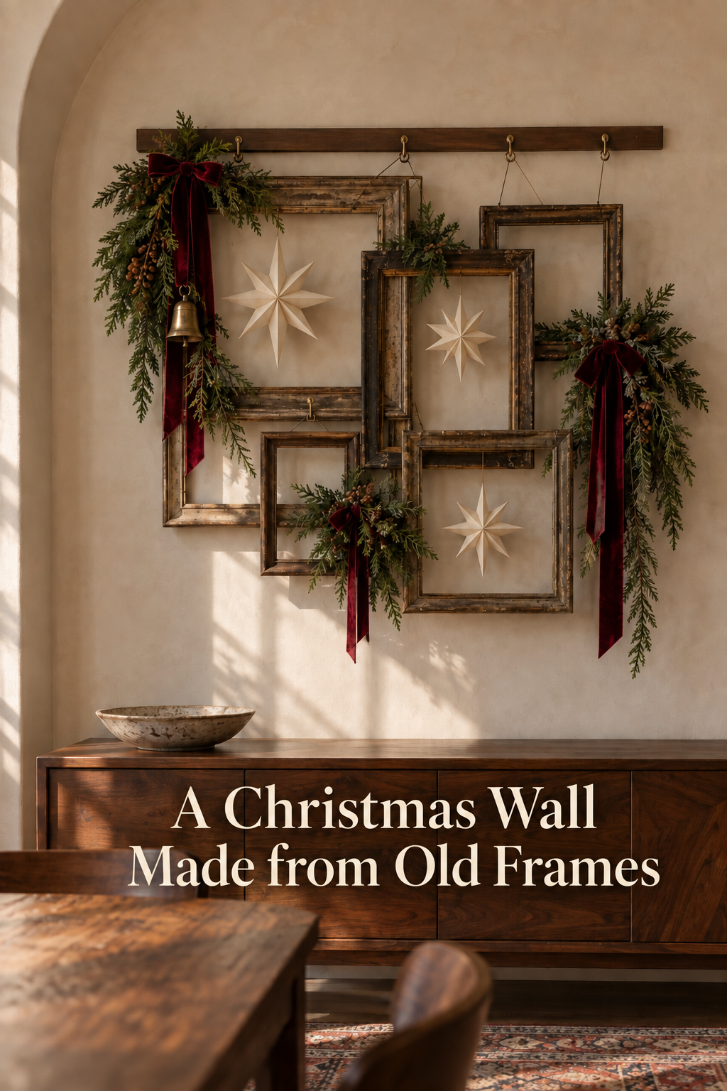Layered vintage frames with paper stars, greenery and burgundy ribbon above a cabinet.