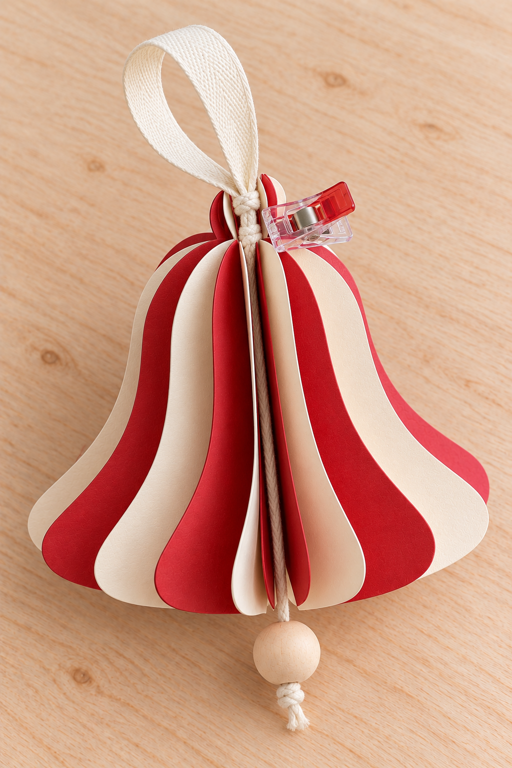 Cream ribbon and cotton cord tied at the paper bell crown beside a seam-holding clip.