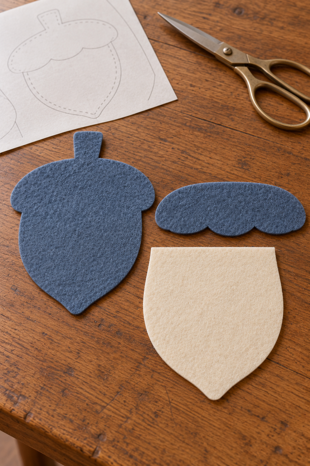 Blue acorn back, ivory front and scalloped blue felt cap cut out separately on a table.