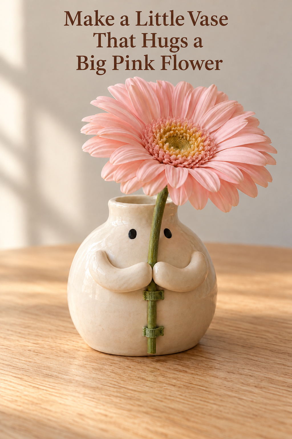 Little ivory vase with black eyes and rounded arms hugging the stem of a big pink daisy.