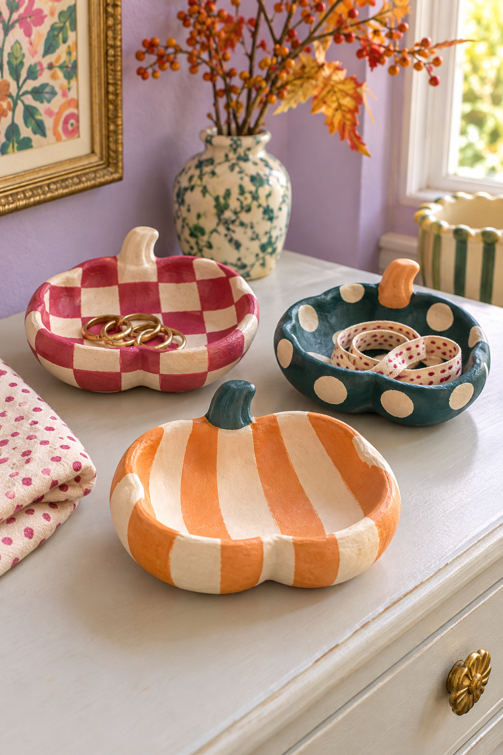 Three pumpkin-shaped dishes with orange stripes, raspberry checks and cream dots on teal.